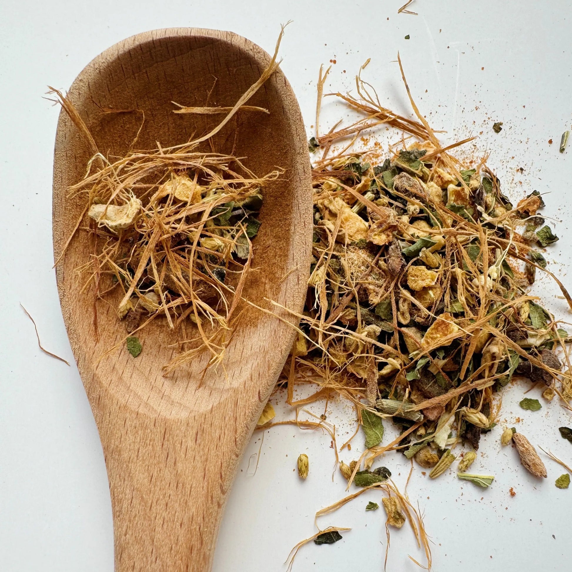 A close-up of loose leaf Immunity Tea blend featuring organic herbs like astragalus root, ginger, wild cherry bark, and echinacea. Displayed on a wooden spoon, the mix includes natural textures and earthy tones, ideal for wellness and immunity.